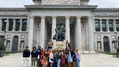 Group of people posing in front of the Prado Museum in Madrid, near the statue of Diego Velázquez.