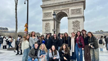A group of people pose in front of the Arc de Triomphe in Paris.