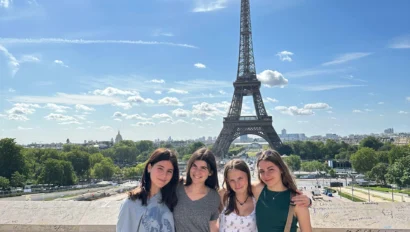Four people standing together in front of the Eiffel Tower on a sunny day.