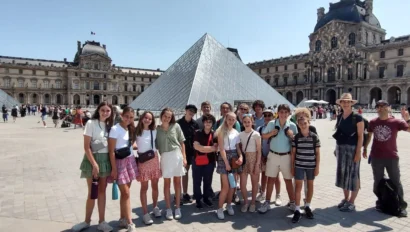 A group of people posing in front of the Louvre Pyramid on a sunny day.