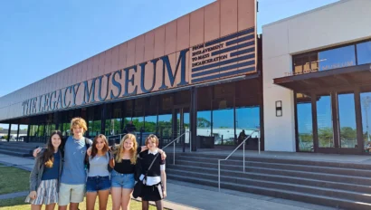 Five people standing together in front of The Legacy Museum with its sign visible above them.