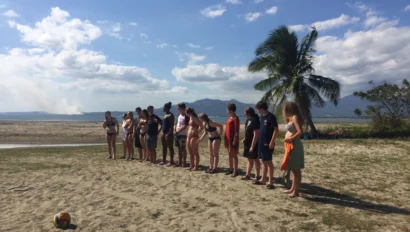 Group of teenagers stand on the beach during an orientation for a trip to Fiji