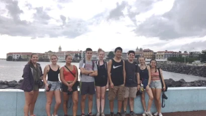 Students sit as a group along a wall near the water in Panama City
