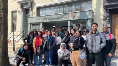 A group of people posing in front of the Carter G. Woodson Home.