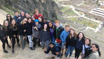 Group of people posing on a hill with a scenic archaeological site and landscape in the background.