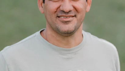 A man in a light gray t-shirt with "A. Eagle USA" stands outdoors on grass, smiling at the camera.