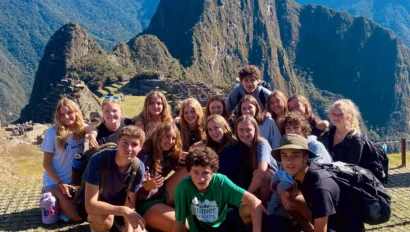A group of people poses for a photo with Machu Picchu and mountains in the background.