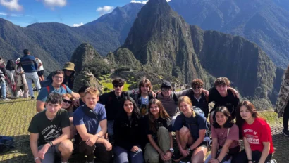 Group of people posing in front of mountainous landscape, with clear skies highlighting the terrain behind them.